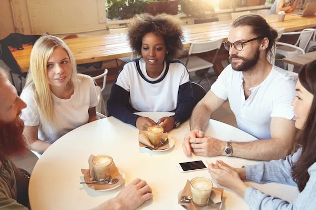 A group of people sitting around a table, in what looks like a community center, discussing and writing on a whiteboard with the words