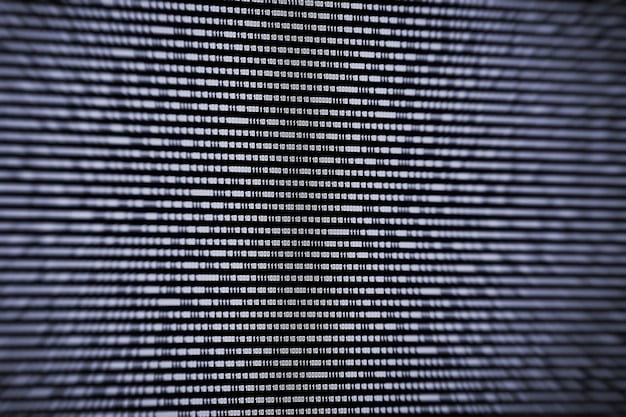 A close-up shot of a computer screen displaying lines of malicious code, with binary numbers (0s and 1s) cascading down the screen. The background is dark and chaotic, symbolizing the uncertainty and complexity of cyber threats. A faint reflection of a hacker's face is visible in the screen, hooded and anonymous.