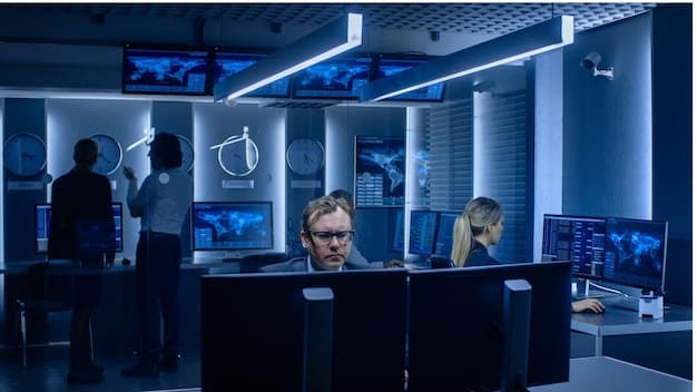 A group of cybersecurity experts in a secure operations center, monitoring screens with real-time threat data and collaborating to mitigate a cyber attack.